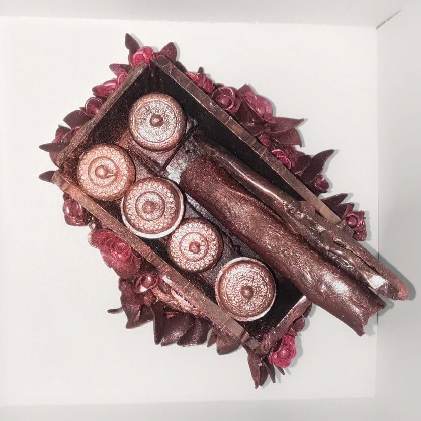 Coklat tepak sireh dilihat dari atas, dengan lima cembul coklat bertutup berderet, setiap tudungnya bercorak, dikelilingi bunga ros coklat merah marun